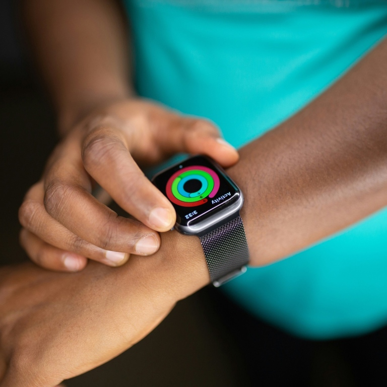 A person adjusts their smart clock on their arm.